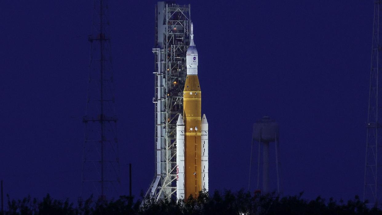  A large orange rocket on a launch pad at night. 