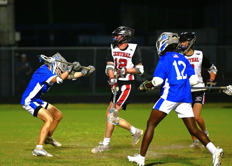 Palm Beach Central's Gavin Miller #12 shoots over the head of a Wellington defender during a lacrosse game on April 3, 2024.