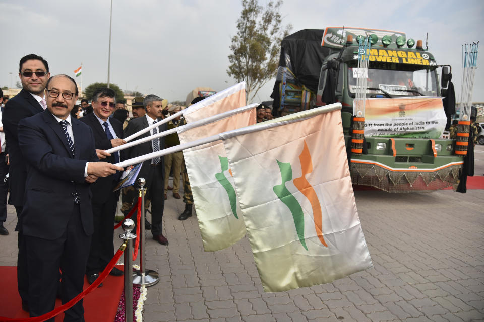 India’s foreign secretary Harsh Vardhan Shringla, second left, and Afghanistan’s ambassador to India Farid Mamundzay, left, flag off the trucks carrying wheat from India at the Attari-Wagah border between India and Pakistan, near Amritsar, India, Tuesday, Feb. 22, 2022. India's foreign ministry says it has sent off tons of wheat to Afghanistan to help relieve desperate food shortages, after New Delhi struck a deal with neighboring rival Pakistan to allow the shipments across the shared border. (AP Photo/Prabhjot Gill)