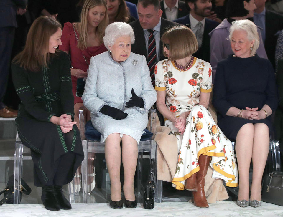 LONDON, ENGLAND - FEBRUARY 20:  Queen Elizabeth II sits with Anna Wintour, Caroline Rush (L), chief executive of the British Fashion Council (BFC) and royal dressmaker Angela Kelly (R) as they view Richard Quinn's runway show before presenting him with the inaugural Queen Elizabeth II Award for British Design as she visits London Fashion Week's BFC Show Space on February 20, 2018 in London, United Kingdom. (Photo by Yui Mok - Pool/Getty Images)