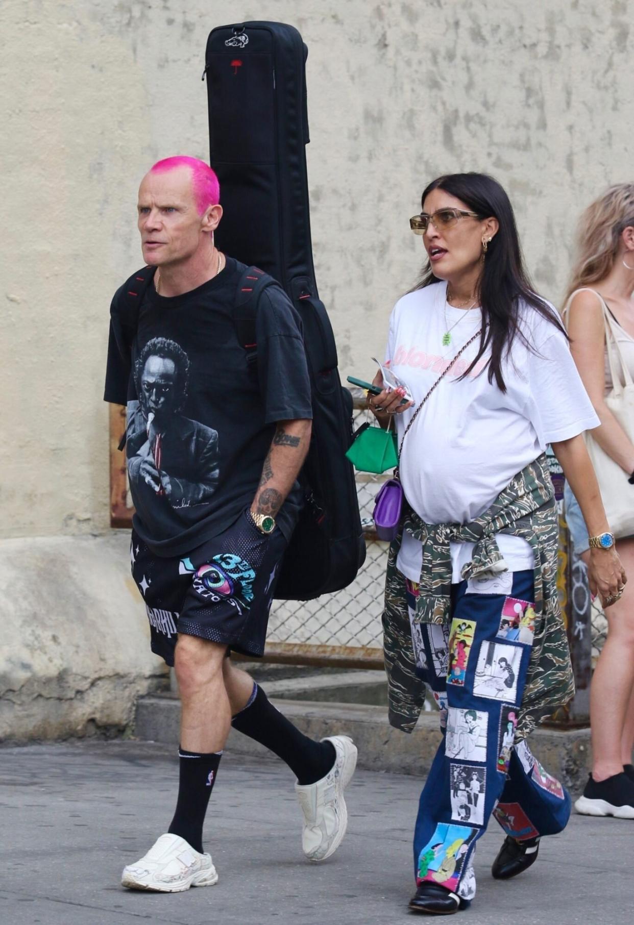 New York, NY - *EXCLUSIVE* - Flea from the Red Hot Chili Peppers, is seen with his pregnant wife Melody Ehsani and the pair is looking stylish in Manhattan’s SoHo area. Flea carries his bass guitar while beating the heat in shorts and turning heads with his bright pink hairdo. Pictured: Flea, Melody Ehsani BACKGRID USA 26 AUGUST 2022 BYLINE MUST READ: BrosNYC / BACKGRID USA: +1 310 798 9111 / usasales@backgrid.com UK: +44 208 344 2007 / uksales@backgrid.com *UK Clients - Pictures Containing Children Please Pixelate Face Prior To Publication*