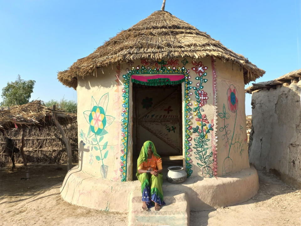 A woman sits on the front step of her home, built to Lari's bamboo, earth and lime designs.<span class="copyright">Heritage Foundation of Pakistan</span>