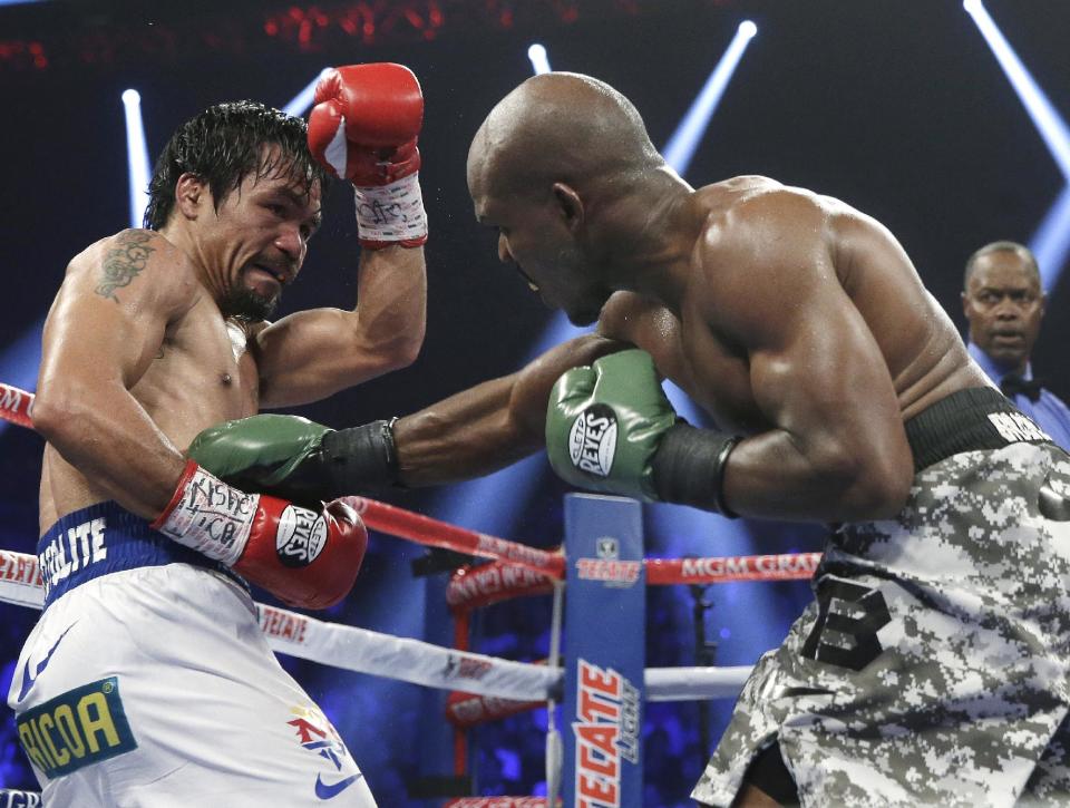 Timothy Bradley, right, connects with a right to the body of Manny Pacquiao, of the Philippines, in their WBO welterweight title boxing fight Saturday, April 12, 2014, in Las Vegas. Pacquiao won the bout by unanimous decision. (AP Photo/Isaac Brekken)