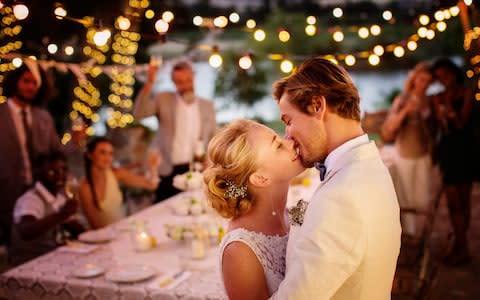 Young couple kissing during wedding reception in domestic garden - Credit: Caiaimage/Tom Merton