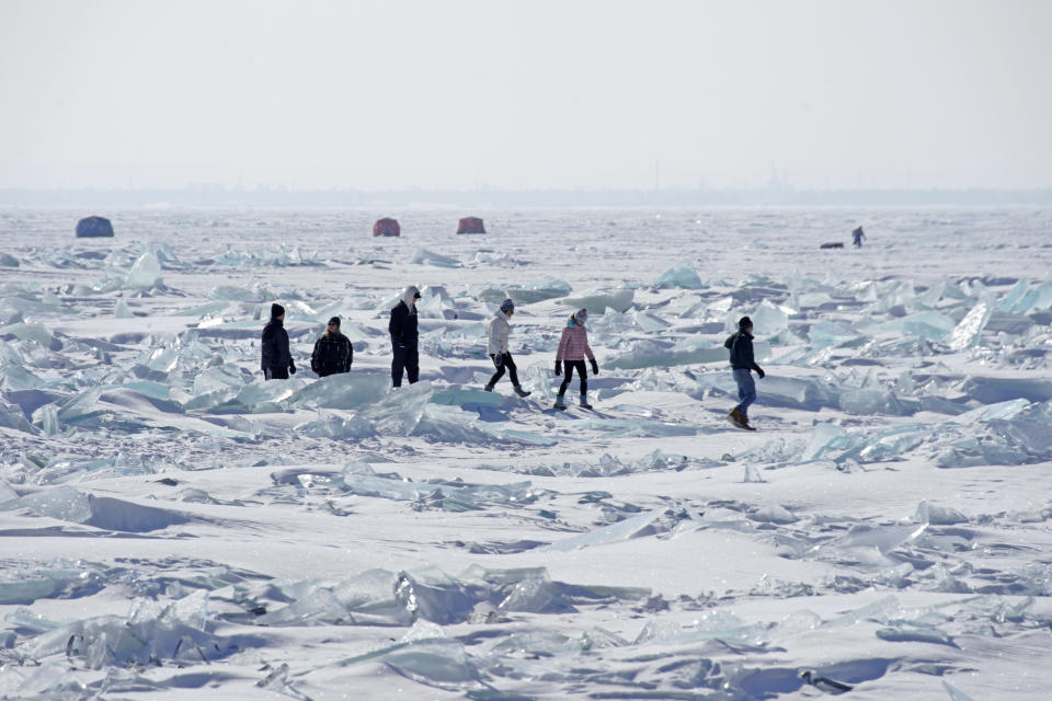 In this Friday, Feb. 22, 2019, photo, people walk on the Ice along the north shore of Lake Superior in Duluth, Minn. Access to the mainland ice caves remain CLOSED. Ice continues to move around quite a bit. Over the last few days, open water has been visible from Meyers Beach as well as near Eagle Island. This ice is typically poor quality ice, which reacts poorly to movement due to weak bonding along the fractures. (Brian Peterson/Star Tribune via AP)