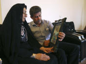 In this picture taken on Monday, April 28, 2014, Iranian woman Samereh Alinejad, left, and her husband Abdolghani Hosseinzadeh whose son Abdollah was killed in a street brawl, look at his picture at their home in the city of Royan about 146 miles (235 kilometers) north of the capital Tehran, Iran. Alinejad tells The Associated Press that she had felt she could never live with herself if the man who killed her son were spared from execution. But in the last moment, she pardoned him in an act that has made her a hero in her hometown, where banners in the streets praise her family’s mercy. (AP Photo/Vahid Salemi)