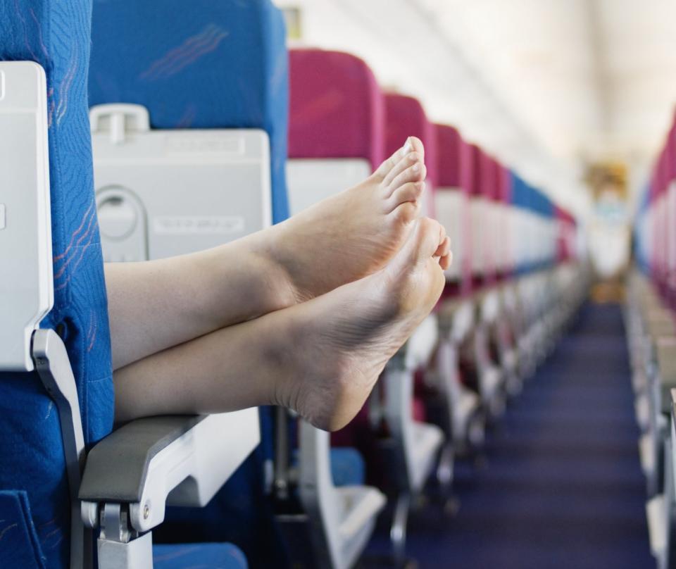 Someone's feet hanging out of the aisle on a plane