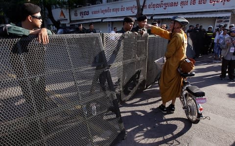 A Buddhist monk tries to enter a blocked street outside the supreme court in Phnom Penh, Cambodia, Thursday, Nov. 16 - Credit: AP