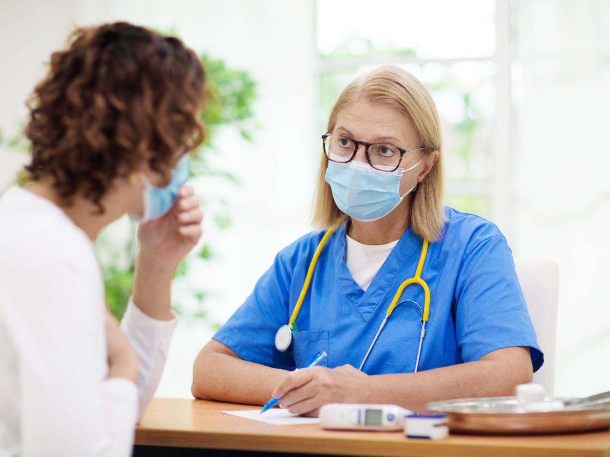 Doctor examining sick patient in face mask. Ill woman in health clinic for test and screening. Home treatment of virus. Coronavirus pandemic. Covid-19 outbreak. Woman coughing, having chest pain.