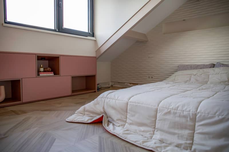 Bed placed against textured wall in master bedroom.