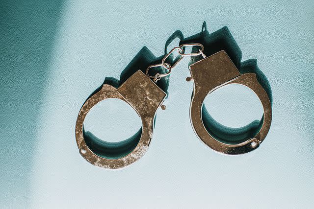 <p>Getty</p> metal handcuffs on blue surface