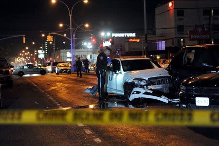 A New York City police officer inspects cars at a crash site in the Brooklyn borough in New York, November 26, 2015. REUTERS/Stephanie Keith