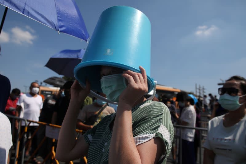 A woman and others line up to buy shrimps from anti government protesters selling shrimps in front of government house amidst the COVID-19 outbreak in Bangkok