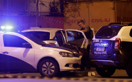 A police investigator inspects the car where Rio de Janeiro city councilor Marielle Franco was shot dead in Rio de Janeiro, Brazil March 15, 2018. REUTERS/Ricardo Moraes