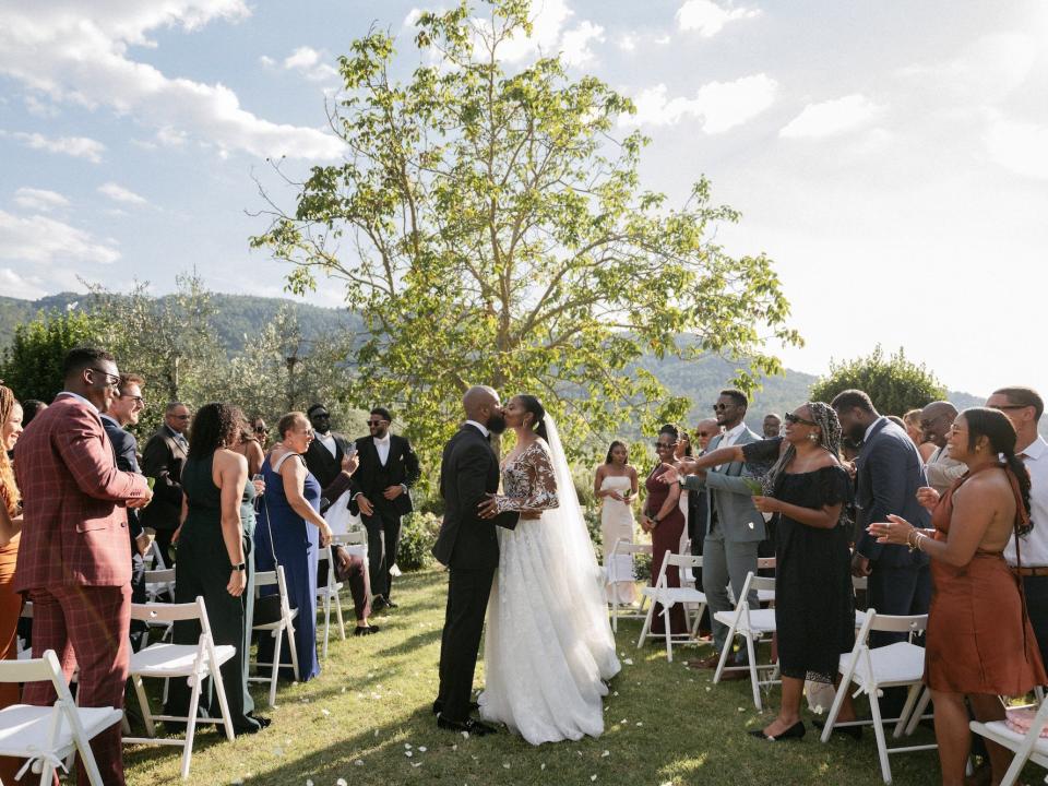 A bride and groom kiss as they walk down their wedding aisle.