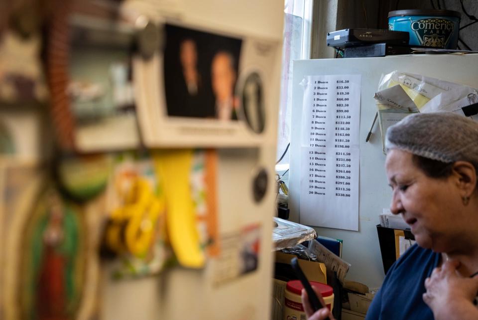 Tamaleria Nuevo Leon owner Susana "Suzy" Villarreal-Garza checks her phone as she stands next to a price list for the tamales she sells inside her business in Detroit's Mexicantown on Thursday, March 2, 2023. Before the pandemic, a bag of a dozen tamales went for $11.50, due to an increase of prices for ingredients during the pandemic, she had to raise the price of a bag to $16.50.