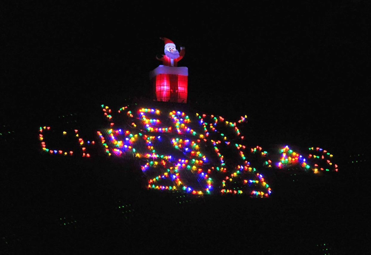 "Merry Christmas 2023" is spelled out in lights on the roof of Tim and Kim Young's Holiday House of Hanson.