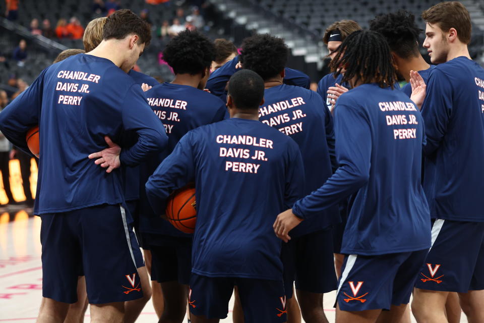 Members of the Virginia basketball team huddle Friday, Nov. 18, 2022, in Las Vegas before an NCAA college basketball game against Baylor, while wearing shirts in memory of the three students killed in a shooting nearly a week ago. (AP Photo/Chase Stevens)