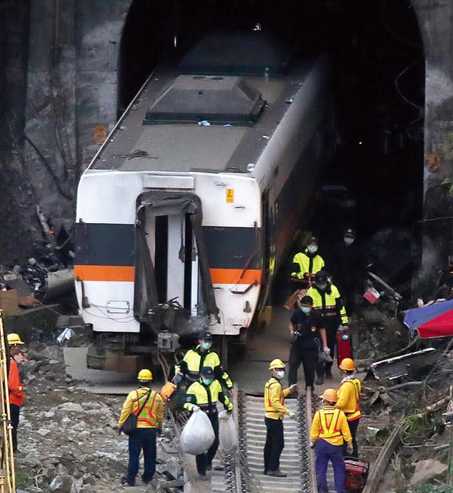 台鐵太魯閣號在花蓮撞工程車出軌意外，4日現場工作人員將原本在隧道中的第四車廂慢慢拖出隧道約半截車廂，就停止拖行，隨後員警進入隧道中提著更多發現的旅客個人行李走出隧道。（鄭任南攝）