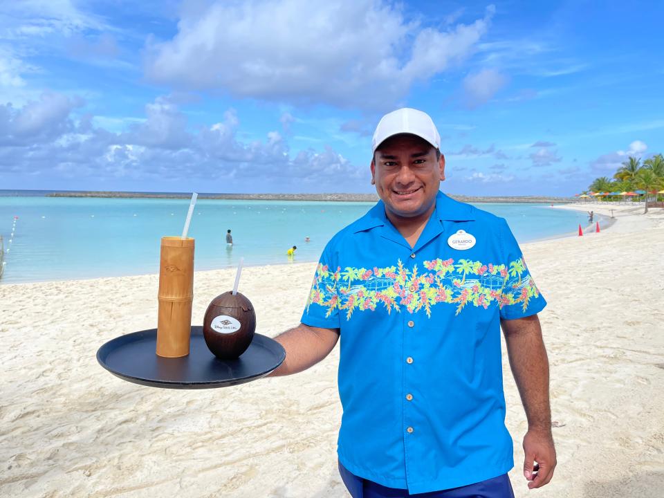 An employee at Castaway Cay holding two drinks on a platter.