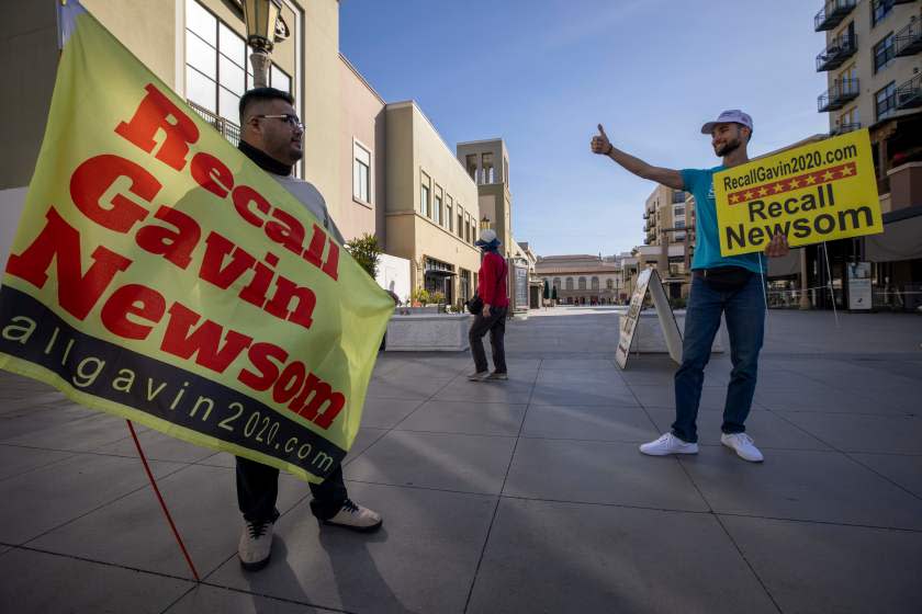 Volunteers try to direct passersby to a booth where conservative activists gather signatures in a recall effort against California Governor Gavin Newsom near Pasadena City Hall, in Pasadena, California on February 28, 2021. (Photo by DAVID MCNEW / AFP) (Photo by DAVID MCNEW/AFP via Getty Images)