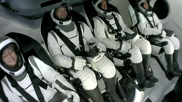 Four Polaris crew sitting strapped in to the capsule wearing their spacesuits 