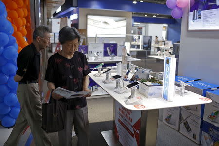 Customers look at mobile phones on display at an electronics market in Shanghai, China, June 24, 2015. REUTERS/Aly Song
