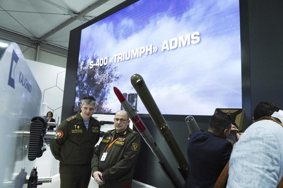 Two Russian military members look at Kalashnikov rifles at a tent for Russian weapons manufacturers at the International Defense Exhibition and Conference in Abu Dhabi, United Arab Emirates, Monday, Feb. 20, 2023. Just outside of Abu Dhabi's biennial arms fair in a large tent, Russia offered weapons for sale Monday ranging from Kalashnikov assault rifles to missile systems despite facing sanctions from the West over its war on Ukraine. (AP Photo/Jon Gambrell)