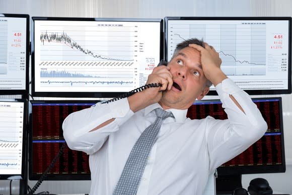 Person on the phone in front of a downward sloping chart.