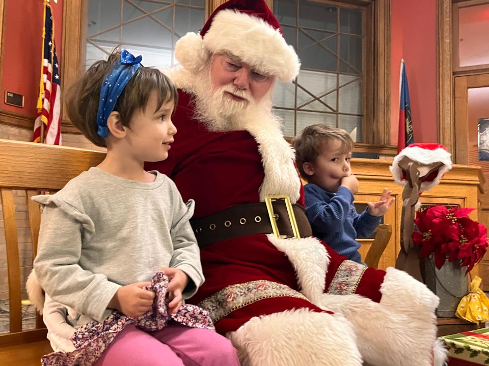 CC Case, 4, of Asheville, answers questions from Santa with her brother, Will Case, 3, inside the Historic Courthouse after the city of Hendersonville’s annual Holiday Tree Lighting Friday, Nov. 24.