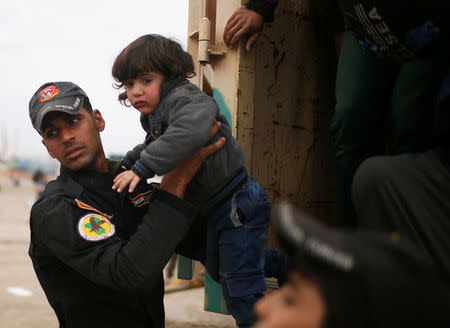 An Iraqi soldier helps a displaced child to get out of a truck as Iraqi forces battle with Islamic State militants, in western Mosul, Iraq March 28, 2017. REUTERS/Suhaib Salem