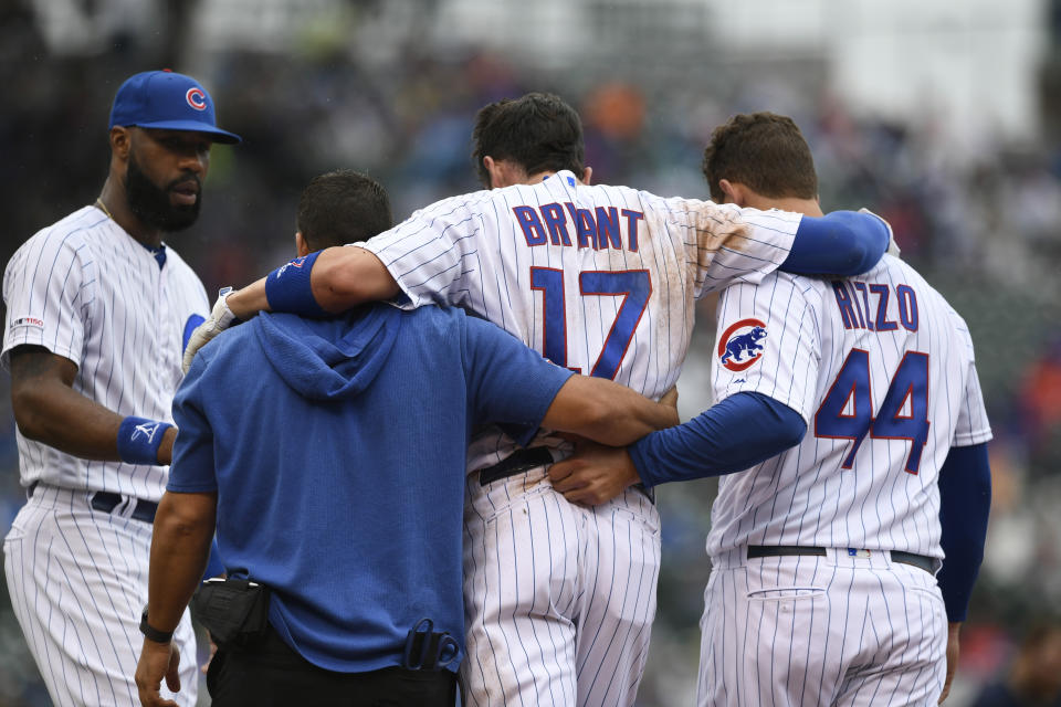 Chicago Cubs' Kris Bryant (17) is helped off the field by teammate Anthony Rizzo (44) and a trainer after getting hurt sliding into first base while teammate Jason Heyward left, looks on during the third inning of a baseball game against the St. Louis Cardinals, Sunday, Sept. 22, 2019, in Chicago. (AP Photo/Paul Beaty)