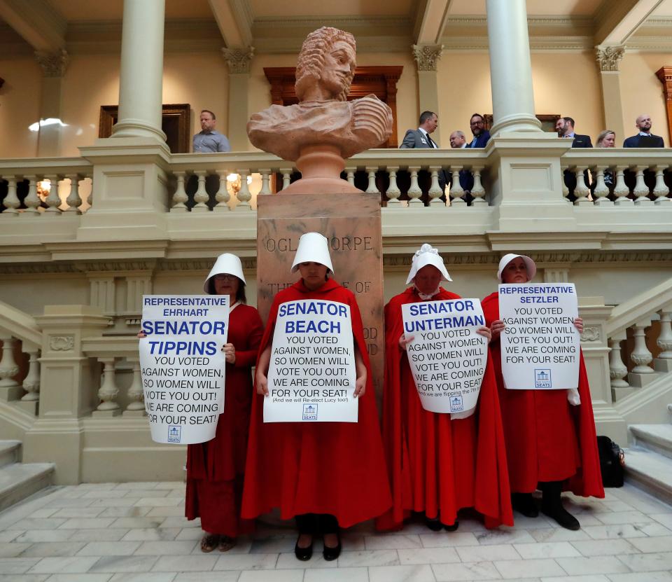 FILE - In this April 2, 2019, file photo, women hold signs to protest HB 481 at the state Capitol in Atlanta. HB 481, which would ban most abortions after a fetal heart beat is detected, has past both the House and the Senate and awaits a signature from Gov. Brian Kemp. (AP Photo/John Bazemore, File)