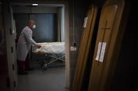 A mortuary worker prepares a coffin carrying the body of a person who died of COVID-19 during a funeral at Memora mortuary in Girona, Spain, Thursday, Feb. 4, 2021. So far in the vaccine race UK vaccination stats have a rate of 15 percent compared to some 3 percent in the EU bloc. The EU has already lost some 480,000 citizens to the pandemic in a bloc of 450 million with more fatalities mounting by the day. (AP Photo/Emilio Morenatti)