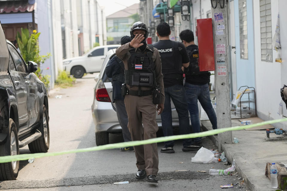 A police officer asks media members move away from an area near a home of a senior police officer in Bangkok, Thailand, Wednesday, March 15, 2023. Thai police on Wednesday detained the senior police officer who fired multiple gunshots from his home in Bangkok, ending a standoff of over 24 hours after his colleagues tried to take him to be treated for mental illness. (AP Photo/Sakchai Lalit)