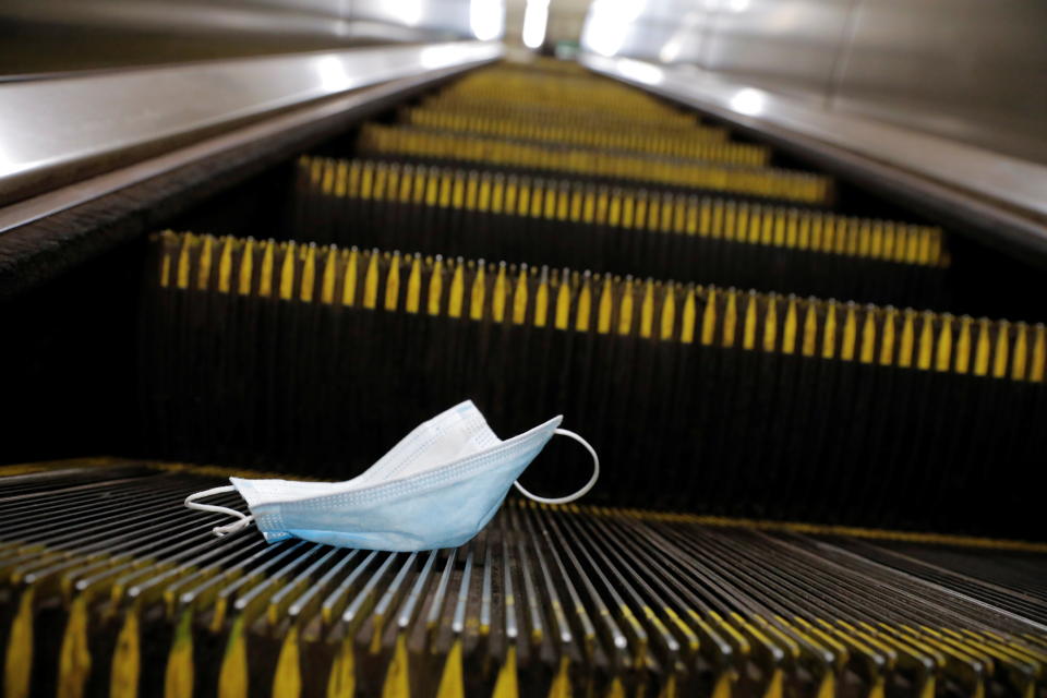 A protective mask is seen discarded on an escalator.