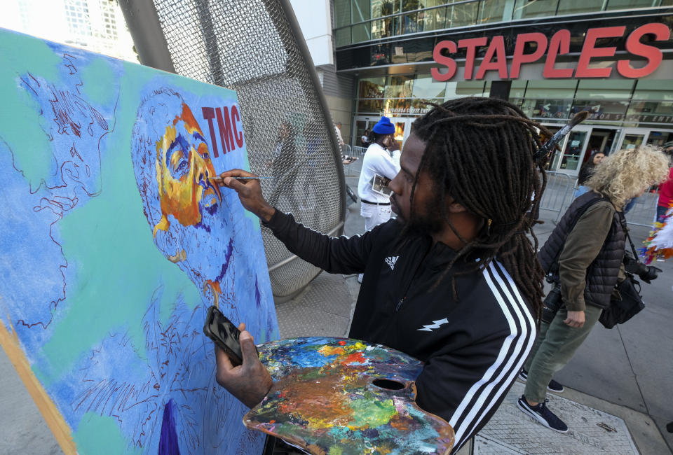 Artist Gift Davis works on a portrait of rapper Nipsey Hussle as fans wait in line to attend a public memorial at Staples Center in Los Angeles, Thursday, April 11, 2019. Hussle was killed in a shooting outside his Marathon Clothing store in south Los Angeles on March 31. (AP Photo/Ringo H.W. Chiu)