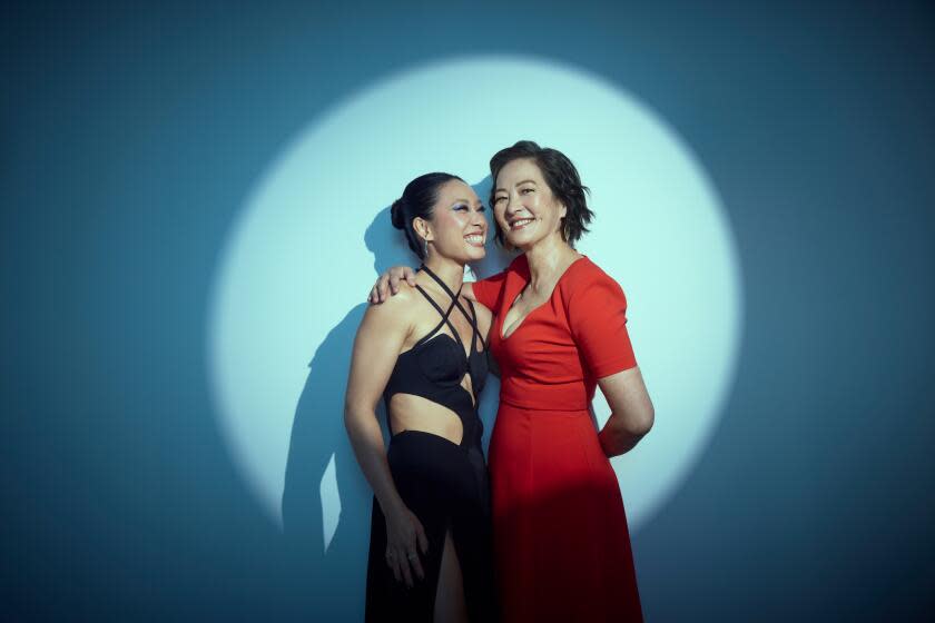 Two smiling women in a spotlight embrace