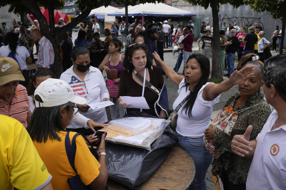 A woman tries to maintain order before to open a polling station during primary election at the Luis Brion square in Caracas, Venezuela, Sunday, Oct. 22, 2023. (AP Photo/Matias Delacroix)