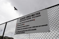 A bird flies above a sign posted on a fence around Cal Anderson Park that lists some of the demands of the Black Lives Matter organization in Seattle, Thursday, June 11, 2020, inside what is being called the "Capitol Hill Autonomous Zone." Following days of violent confrontations with protesters, police in Seattle have largely withdrawn from the neighborhood, and protesters have created a festival-like scene that has President Donald Trump fuming. (AP Photo/Ted S. Warren)