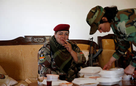 Iraqi Kurdish female fighter Haseba Nauzad, 24, smokes a cigarette after having lunch with Yazidi female fighter Asema Dahir (R), 21, at a site near the frontline of the fight against Islamic State militants in Nawaran near Mosul, Iraq, April 20, 2016. REUTERS/Ahmed Jadallah