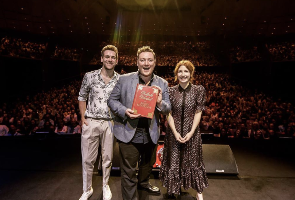 James Cooper, Jamie Morton and  Alice Levine pose on stage at My Dad Wrote a Porno tour holding Belinda Blinked