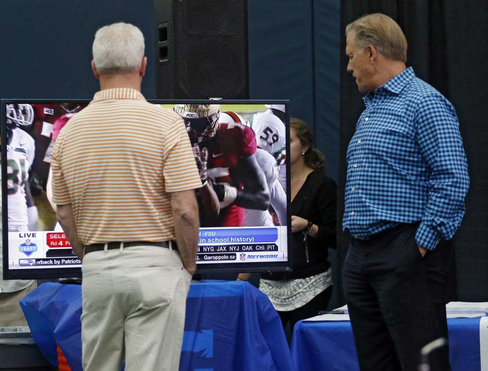 Denver Broncos head coach John Fox and vice president John Elway, right, keep up with the NFL draft on a television in the media center as second round draft pick Indiana wide receiver Cody Latimer speaks to the media at the NFL football teams headquarters in Englewood, Colo., on Saturday, May 10, 2014. (AP Photo/Ed Andrieski)