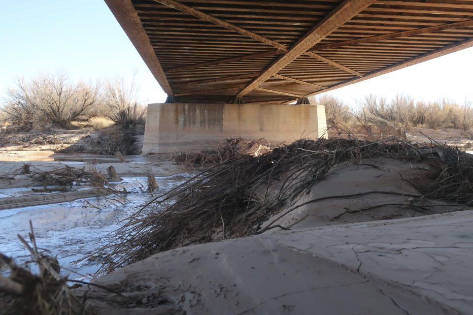 Mud and debris sits under a railroad bridge that crosses the Little Colorado River in Winslow, Arizona, on Feb. 4, 2022. The U.S. Army Corps of Engineers recently announced a flood control project in the city would receive $65 million in funding. (AP Photo/Felicia Fonseca)