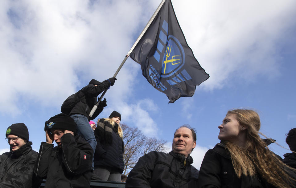 A woman waves the flag of the Farmers Defense Force during a demonstration in The Hague, Netherlands, Wednesday, Feb. 19, 2020. Dutch farmers, some driving tractors, poured into The Hague on Wednesday to protest government moves to rein in carbon and nitrogen emissions to better fight climate change. (AP Photo/Peter Dejong)