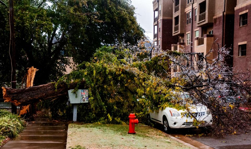 A broken tree covers a car in Oklahoma City, Okla. on Tuesday, Oct. 27, 2020, after a winter blast covered the state with ice.