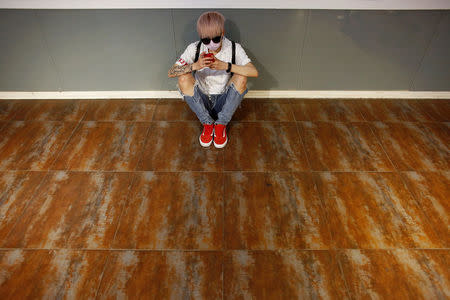 A member of China's all-girl "boyband" FFC-Acrush uses her phone before a rehearsal at a dance studio in Beijing April 27, 2017. REUTERS/Thomas Peter