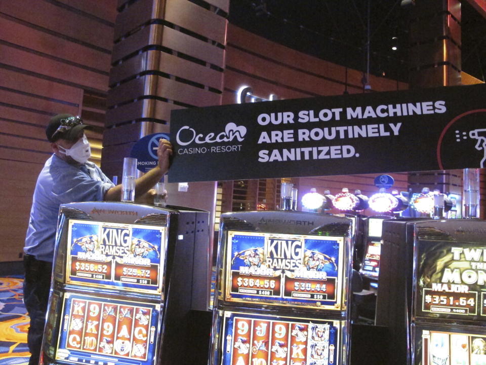 A worker at the Ocean Casino Resort in Atlantic City N.J. installs a sign indicating that slot machines will routinely be sanitized once the casino reopened a month later to prevent the spread of the coronavirus, June 3, 2020. The New Jersey Supreme Court is expected to hear arguments, Wednesday, Sept. 27, 2023, in a case involving whether insurance companies were correct in denying payouts to the casino for business losses during the state-mandated closure in 2020. (AP Photo/Wayne Parry)