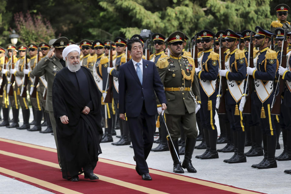 Japanese Prime Minister Shinzo Abe, center, reviews an honor guard as he is welcomed by Iranian President Hassan Rouhani, left, in an official arrival ceremony at the Saadabad Palace in Tehran, Iran, Wednesday, June 12, 2019. The Japanese leader is in Tehran on an mission to calm tensions between the U.S. and Iran. (AP Photo/Ebrahim Noroozi)