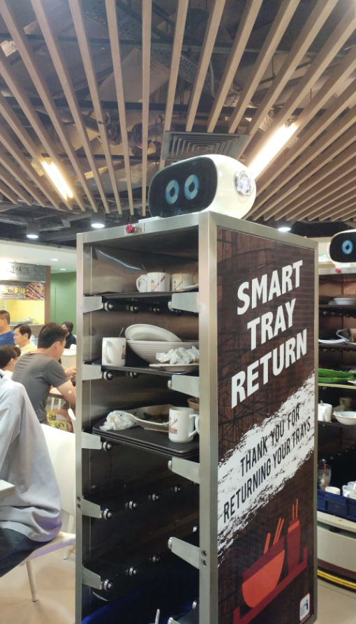 Smart tray return station with a "Thank You for Returning Your Tray" sign in a busy food court